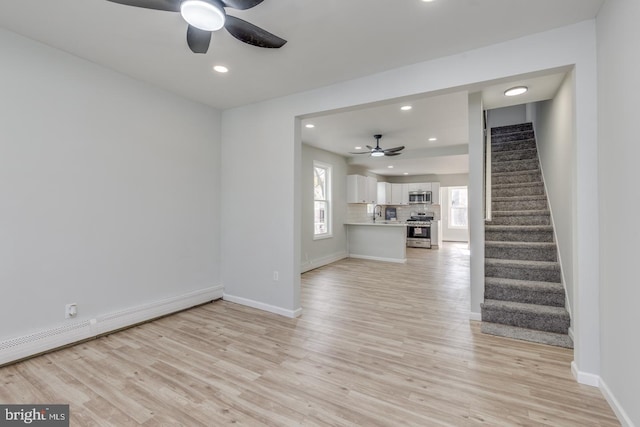 unfurnished living room with ceiling fan, light hardwood / wood-style flooring, and a baseboard heating unit