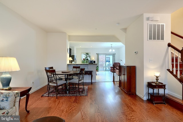 dining space featuring hardwood / wood-style flooring and an inviting chandelier