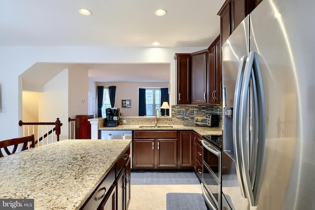 kitchen featuring backsplash, light stone countertops, sink, and appliances with stainless steel finishes