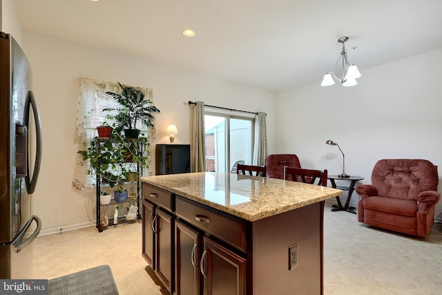 kitchen with stainless steel fridge with ice dispenser, light stone counters, a notable chandelier, pendant lighting, and a kitchen island