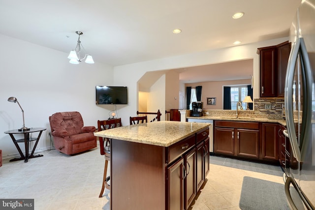 kitchen with stainless steel appliances, decorative light fixtures, a chandelier, a kitchen island, and a breakfast bar area