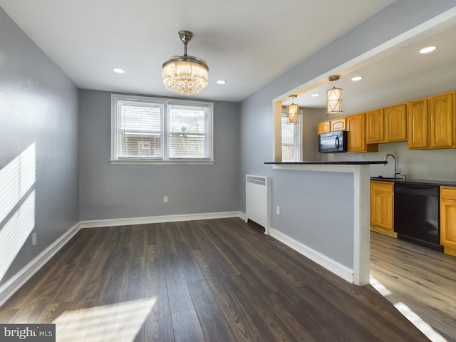 kitchen with dark wood-type flooring, hanging light fixtures, black appliances, and sink