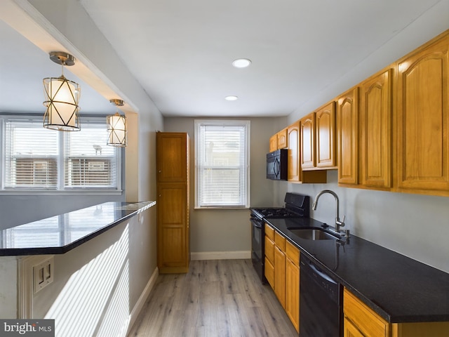 kitchen featuring black appliances, decorative light fixtures, light wood-type flooring, and sink