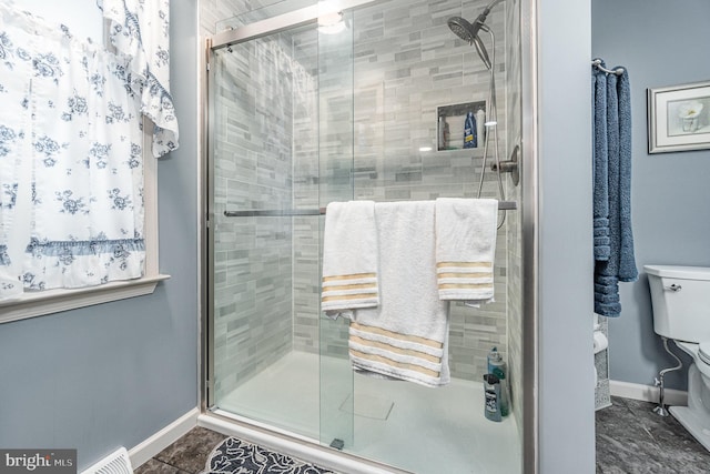 bathroom featuring a shower with shower door and toilet