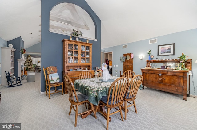 dining area featuring light colored carpet and lofted ceiling