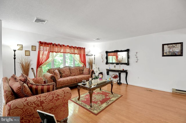 living room with baseboard heating, wood-type flooring, and a textured ceiling