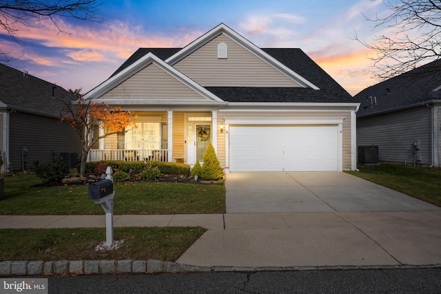 view of front of home with a lawn, central AC unit, a porch, and a garage