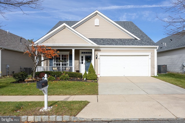 view of front of property featuring covered porch, cooling unit, a garage, and a front yard