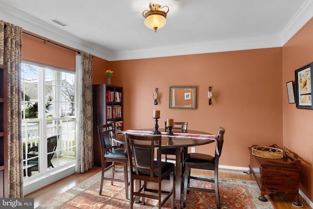 dining room featuring light wood-type flooring and crown molding