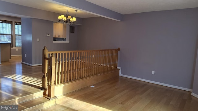 stairway featuring beamed ceiling, hardwood / wood-style floors, and a notable chandelier