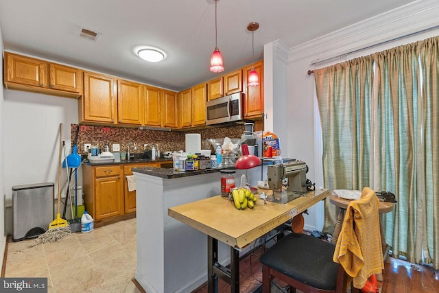 kitchen featuring sink, ornamental molding, tasteful backsplash, decorative light fixtures, and kitchen peninsula