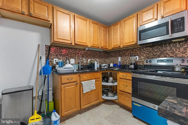 kitchen with backsplash, sink, dark stone counters, and stainless steel appliances