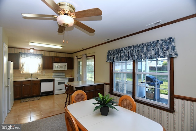 tiled dining area with ceiling fan, sink, and crown molding