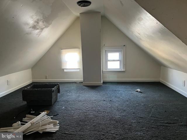 additional living space with dark carpet and vaulted ceiling