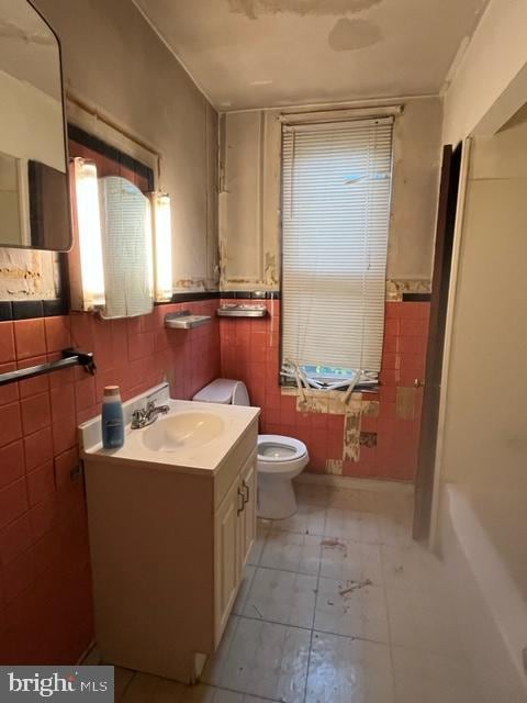 bathroom with tile patterned flooring, vanity, toilet, and tile walls