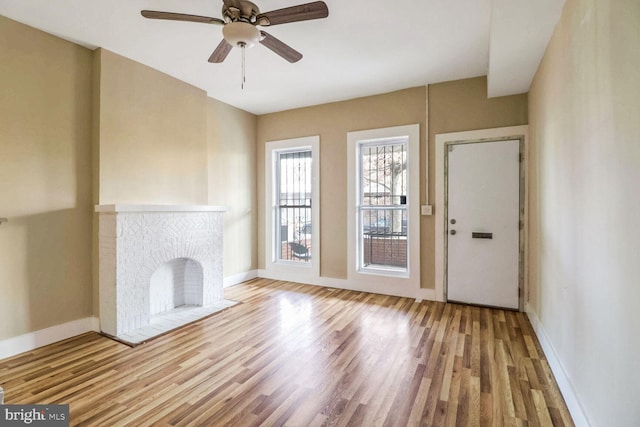 unfurnished living room featuring a fireplace, light wood-type flooring, and ceiling fan