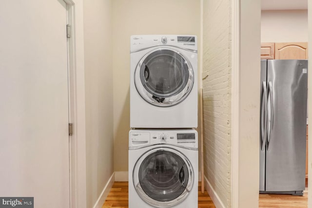 washroom with light wood-type flooring and stacked washer and dryer