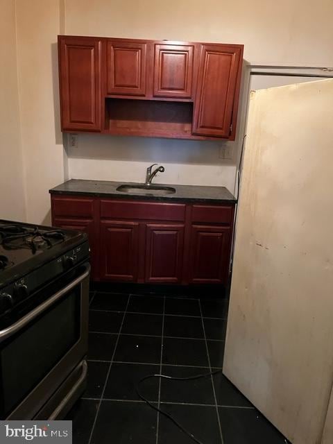 kitchen featuring dark tile patterned flooring, black gas range, and sink