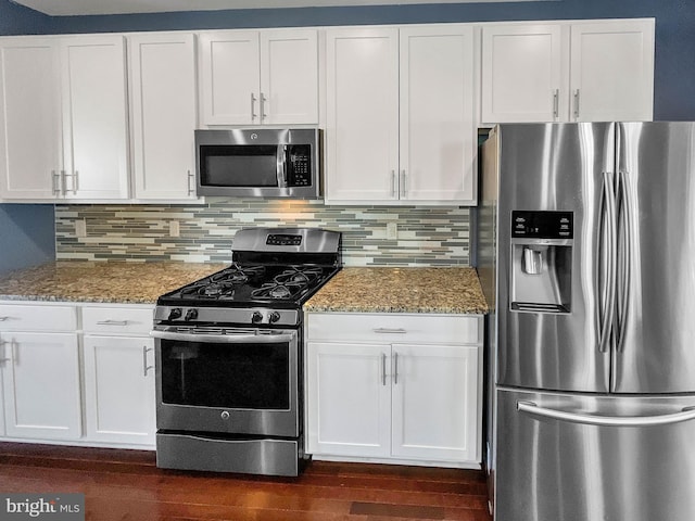 kitchen featuring white cabinetry, appliances with stainless steel finishes, and dark stone counters