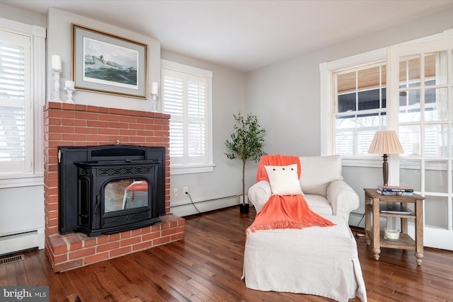 living area with a healthy amount of sunlight, dark hardwood / wood-style floors, and a baseboard heating unit