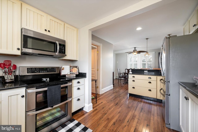 kitchen with cream cabinets, dark wood-type flooring, ceiling fan, and appliances with stainless steel finishes