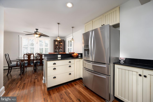 kitchen featuring stainless steel fridge, dark hardwood / wood-style floors, kitchen peninsula, decorative light fixtures, and cream cabinetry