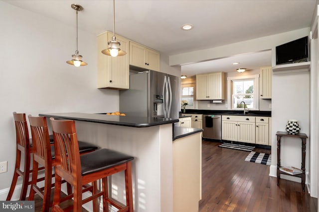 kitchen featuring dark hardwood / wood-style floors, pendant lighting, sink, a kitchen breakfast bar, and stainless steel appliances