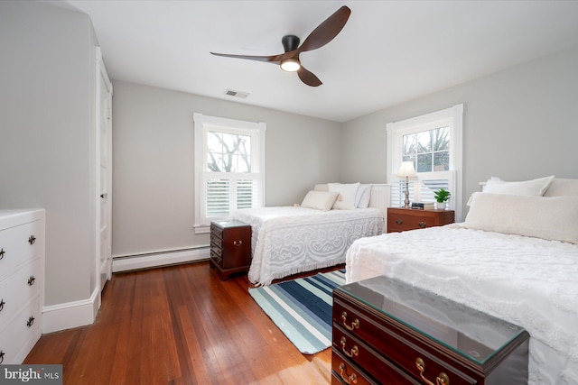 bedroom with a baseboard heating unit, dark wood-type flooring, and ceiling fan