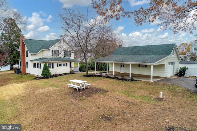 view of front of property featuring a garage, central AC, a front lawn, and a porch