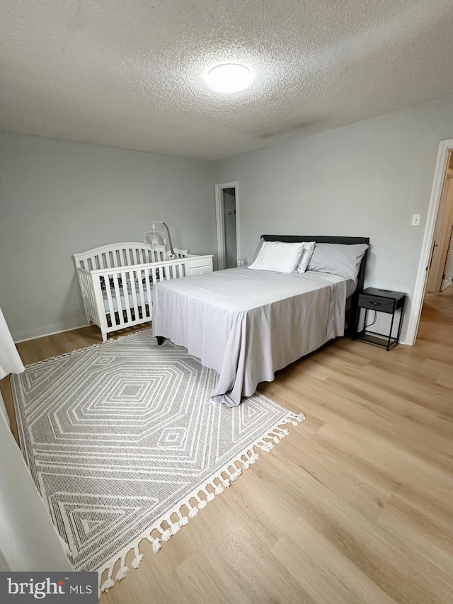 bedroom featuring a textured ceiling and light hardwood / wood-style flooring