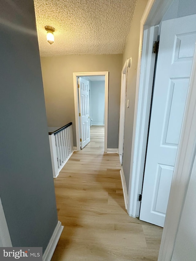 hall featuring light hardwood / wood-style floors and a textured ceiling