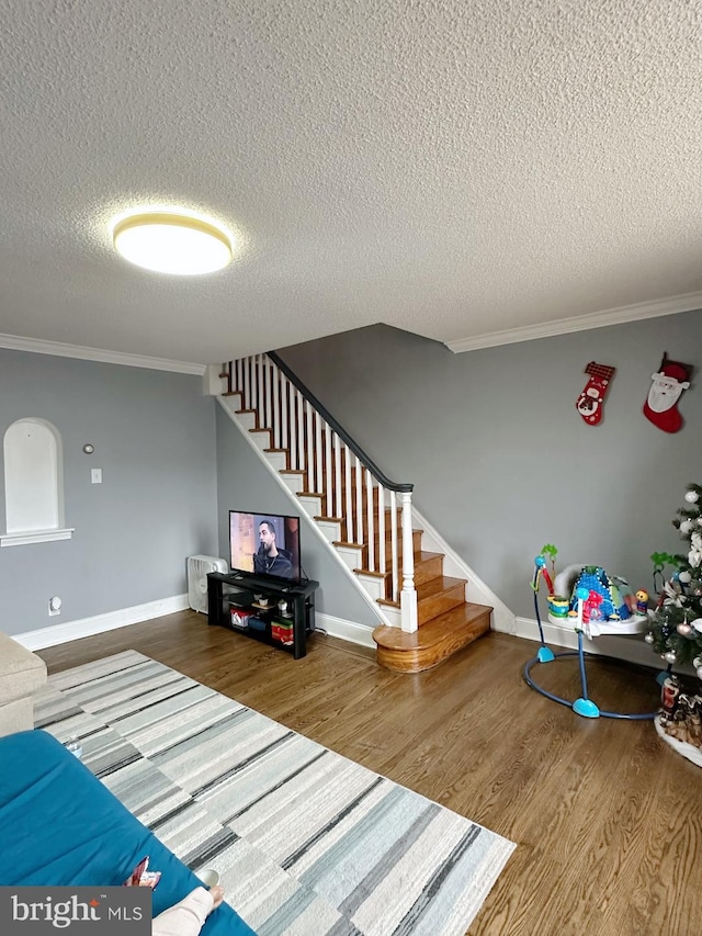 living room with hardwood / wood-style floors, a textured ceiling, and crown molding