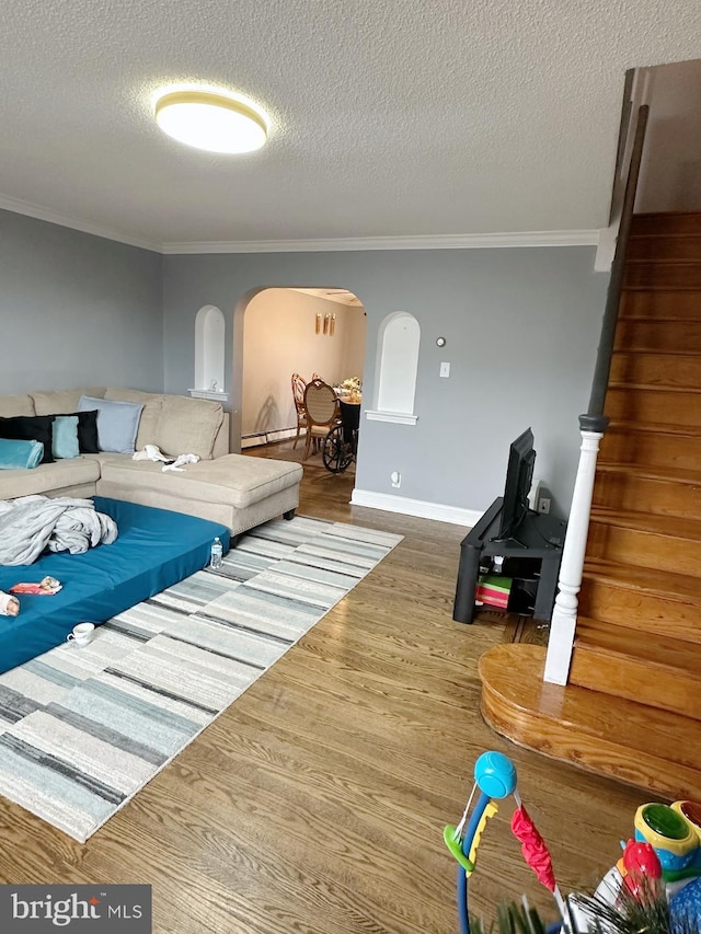 living room with wood-type flooring, a textured ceiling, a baseboard heating unit, and ornamental molding