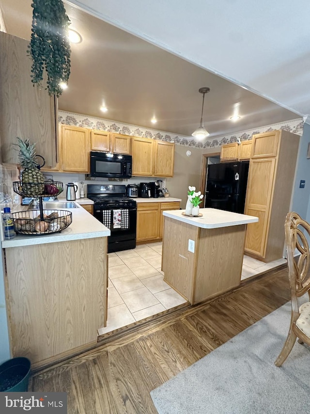 kitchen featuring decorative light fixtures, a center island, light hardwood / wood-style floors, and black appliances