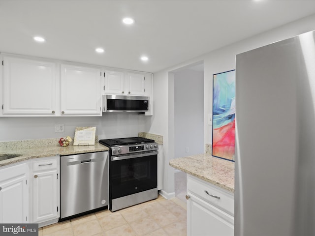 kitchen with white cabinets, stainless steel appliances, and light stone counters