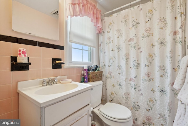 bathroom with vanity, toilet, tile walls, and walk in shower