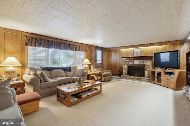 carpeted living room with a stone fireplace and wooden walls