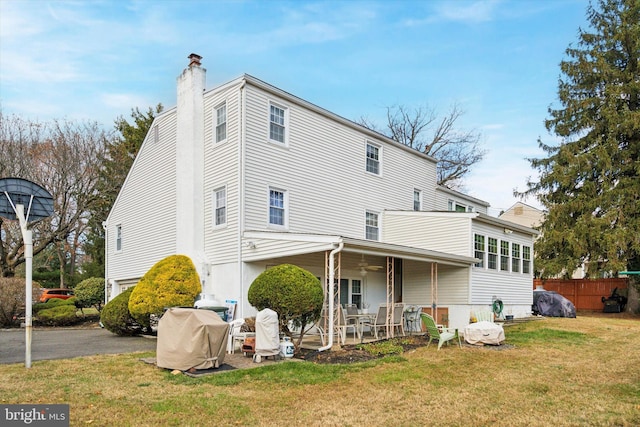 rear view of property featuring ceiling fan, a yard, and a patio