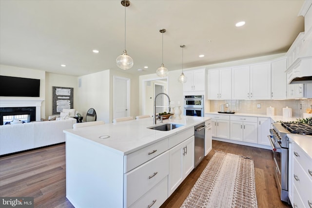 kitchen with stainless steel appliances, dark hardwood / wood-style floors, a center island with sink, and sink