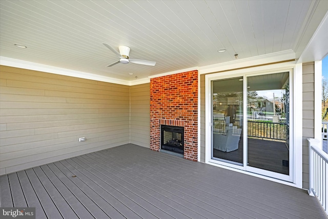 deck with an outdoor brick fireplace and ceiling fan