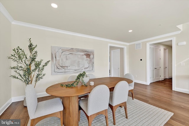 dining room with ornamental molding and hardwood / wood-style flooring