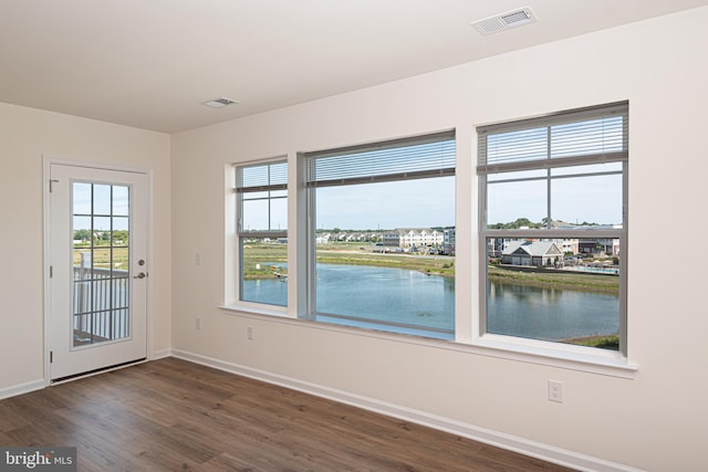 unfurnished room featuring dark hardwood / wood-style flooring, a water view, and plenty of natural light