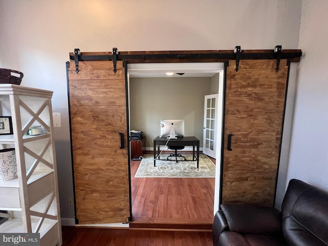 doorway with dark wood-style floors, baseboards, and a barn door