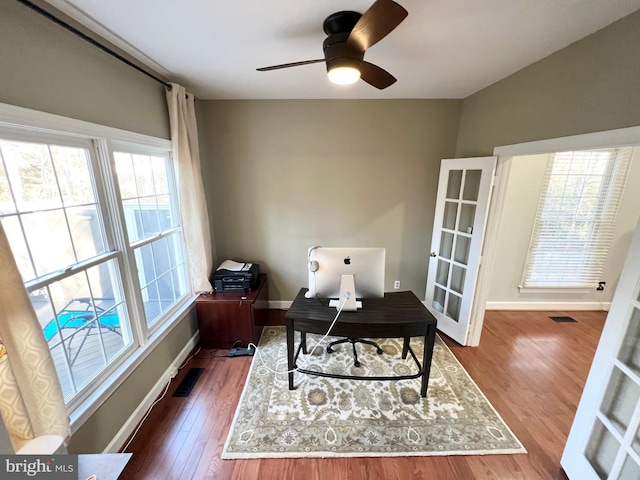 office area with plenty of natural light, wood finished floors, visible vents, and baseboards