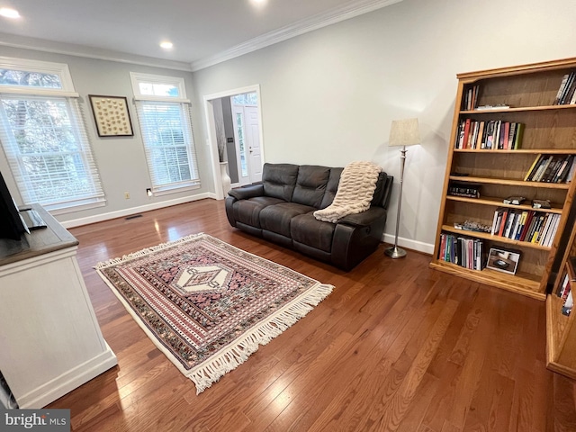 living area featuring wood finished floors, baseboards, and ornamental molding