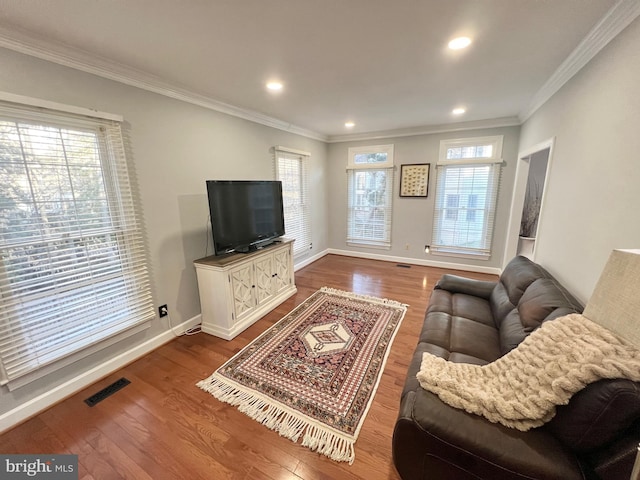 living area featuring visible vents, baseboards, wood finished floors, and ornamental molding