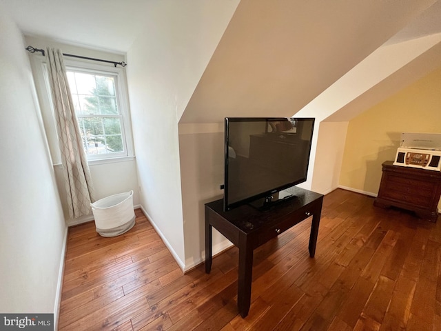 living area with hardwood / wood-style flooring, baseboards, and vaulted ceiling