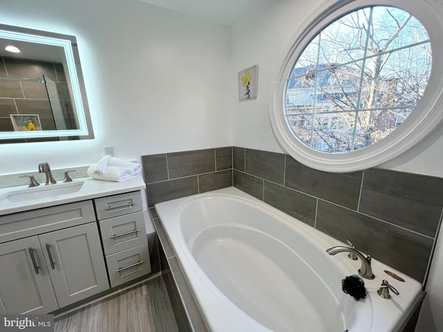 full bath with a bath, tiled shower, and vanity