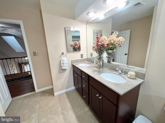 bathroom featuring double vanity, visible vents, baseboards, and a sink