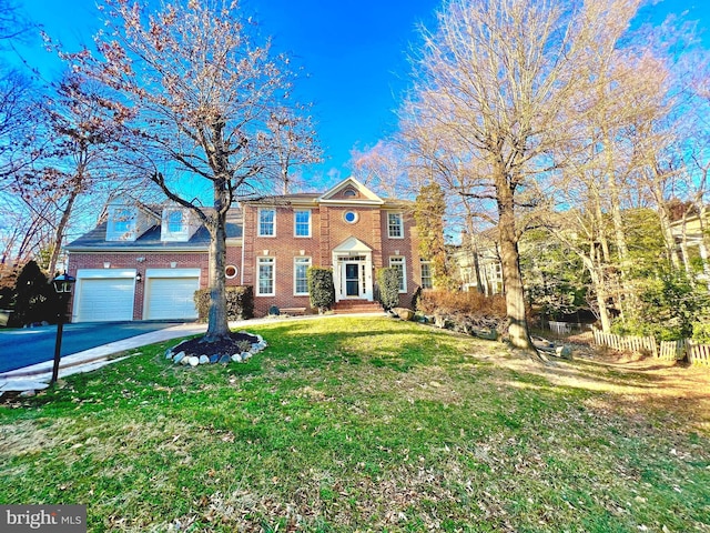 view of front of house featuring brick siding, an attached garage, a front lawn, fence, and driveway